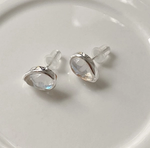 Detail of 925 silver stud earrings with iridescent round stones on white ceramic