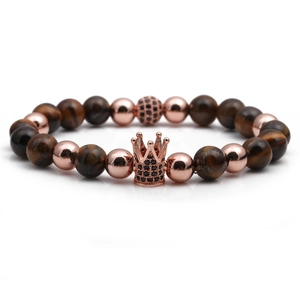 Macro detail of brown tiger eye beads and rose gold crown charm with black zircons
