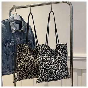 Minimalist leopard print tote bags in brown and white hanging with a denim jacket