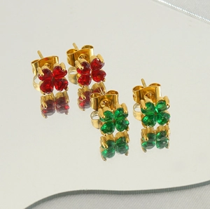 Gros plan de boucles d'oreilles trèfles en acier doré avec zircons rouges et verts