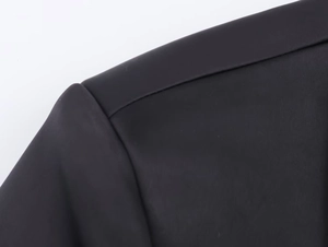 Close-up of shoulder seam craftsmanship and black herringbone wool fabric texture