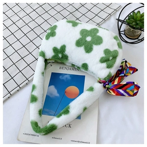 Detail of plush tote bag with green daisy patterns and decorative silk scarf on handle