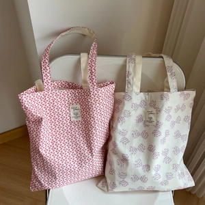 Détail de sacs fourre-tout en toile à motifs de nœuds posés sur une chaise blanche