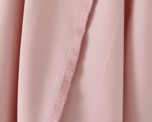 Gros plan détaillé du tissu de robe rose montrant la couture surjetée et la texture