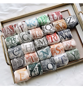 Floral letter print silk twilly scarves neatly arranged in a luxury golden tray display