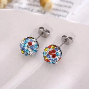 Gros plan de boucles d'oreilles boules pavées de cristaux colorés sur un plateau en céramique