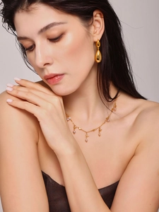 Detail of 18K gold plated teardrop earrings and pink pearl necklace set on a model