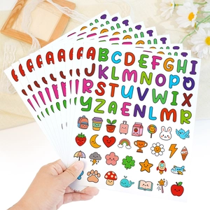 Hand holding colorful cartoon alphabet and icon stickers for DIY water bottle decoration