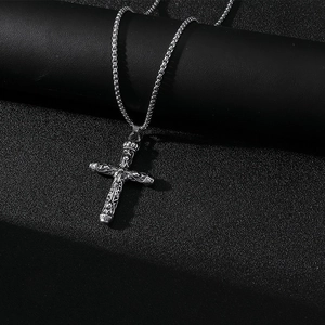 Détail macro d'un pendentif croix en acier inoxydable argenté aux motifs gaufrés