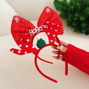 Detail of a Christmas headband with red polka dot antlers and HoHoHo text held by hand
