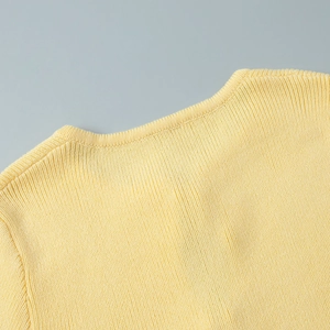 Close-up of pale yellow ribbed knit neckline with fine stitching and soft texture