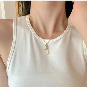 Close-up of gold moon and star tassel necklace with zircons on model neck