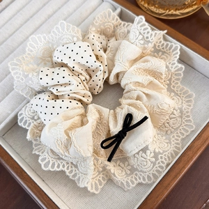 Detailed close-up of a lace patchwork hair scrunchie with a small black bow decoration