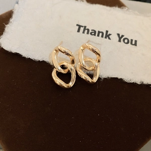 Elegant gold geometric chain link stud earrings displayed on a dark velvet jewelry box
