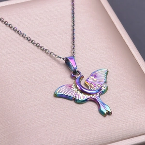 Detailed shot of iridescent moon and moth pendant necklace on pink jewelry box