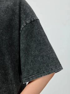 Detail of washed cotton fabric texture and shoulder stitching on a charcoal grey T-shirt