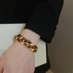 Detailed view of leopard print link bracelet worn with a professional black blazer