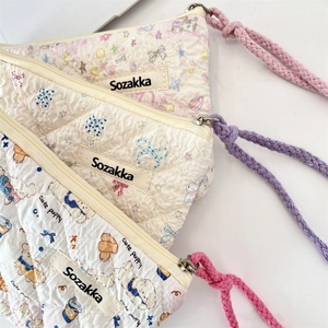 Close-up of quilted floral cosmetic bags with cotton rope zippers and soft textures