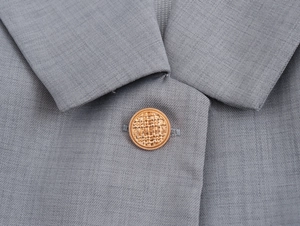 Gros plan d'un bouton doré décoratif sur le tissu gris d'un costume élégant