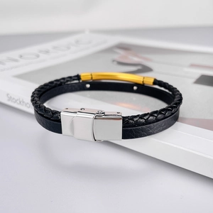 Gros plan d'un bracelet en cuir tressé noir avec barres dorées sur un magazine