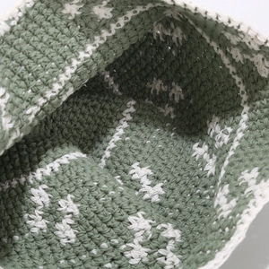 Close-up of handmade crochet texture in forest green and cream white yarn detail