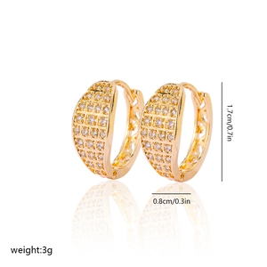 Detail of gold zircon earrings with hollow pattern and mirror reflection on white base