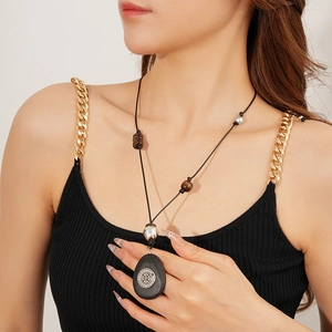 Collier ethnique avec pendentif ovale en bois et détails argentés porté par un mannequin