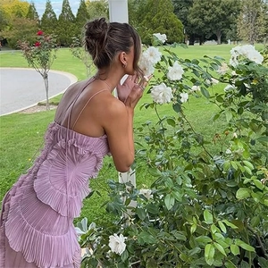 Détail de la robe violette à volants avec bretelles portée par un mannequin en jardin