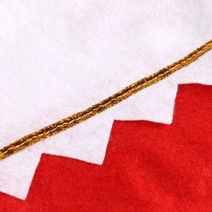 Close-up of red and white Christmas stocking fabric with golden metallic woven trim detail