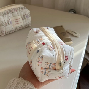 Detailed view of hand-held quilted cotton pouch with cute puppy and cherry patterns