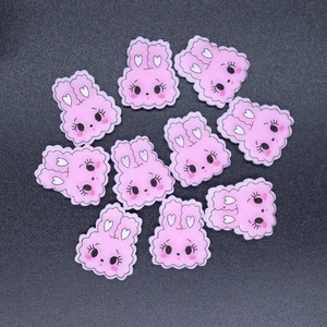 Flat lay of 10 pink resin bunny charms for DIY phone case crafts and accessories