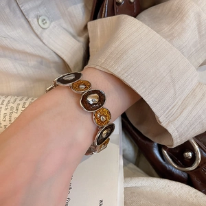 Detail of vintage enamel irregular stretch bracelet on wrist with warm lifestyle lighting