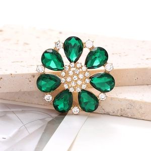Detailed macro view of a green rhinestone flower charm with emerald stones and gold base