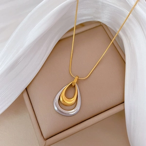 Double-layered water drop necklace in gold and silver steel on a satin jewelry display