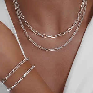 Close-up of double-layered silver paperclip chain necklace and bracelet on model