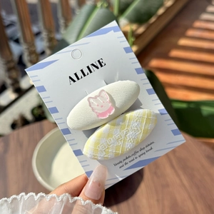 Close-up of pink cat clip and yellow plaid puppy hairpins on brand display card