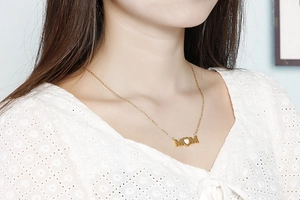 Close-up of golden MOM heart necklace worn on collarbone showing the polished metal texture