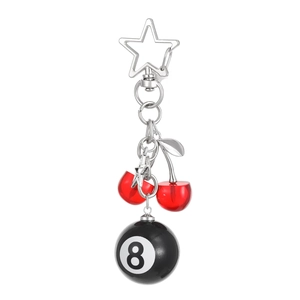 Detail of red cherry pendant, black billiard ball 8 charm, and silver star keychain