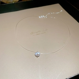 Dettaglio della collana invisibile minimalista con pendente in zircone rotondo su carta