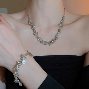 Detail of silver drop fringe necklace and bracelet set worn on neck and wrist