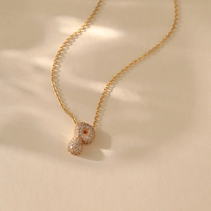 Macro shot of gold-plated necklace featuring a letter P pendant with zircon pavé