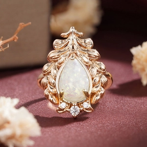 Macro detail of pear-shaped white opal ring with rose gold leaf textures and zircons