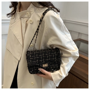 Model wearing a black tweed shoulder bag with a gold-tone chain strap and metal clasp