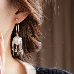 Détail de boucles d'oreilles argentées en C avec cage à perles et pampilles d'étoiles