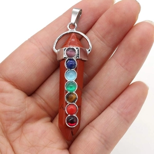Détail d'un pendentif en cristal hexagonal orné de sept pierres précieuses de chakra