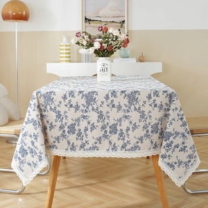 Elegant blue floral linen tablecloth with white lace trim in a cozy dining room.