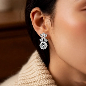 Dettaglio di orecchini a fiore in argento con zirconi indossati da una modella donna