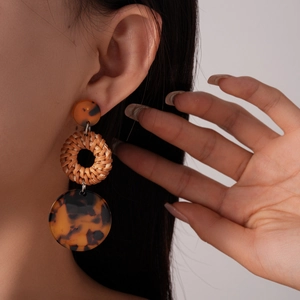 Detail of bohemian resin earrings with woven rattan and tortoiseshell texture on model