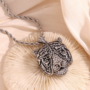 Close-up of vintage silver tiger head pendant with white rhinestones on twisted chain