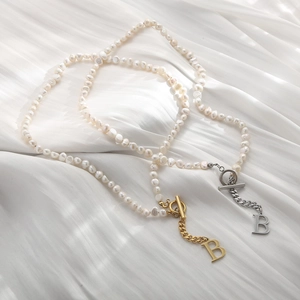 Detailed view of baroque pearl necklaces with OT buckle and metallic B letter pendant